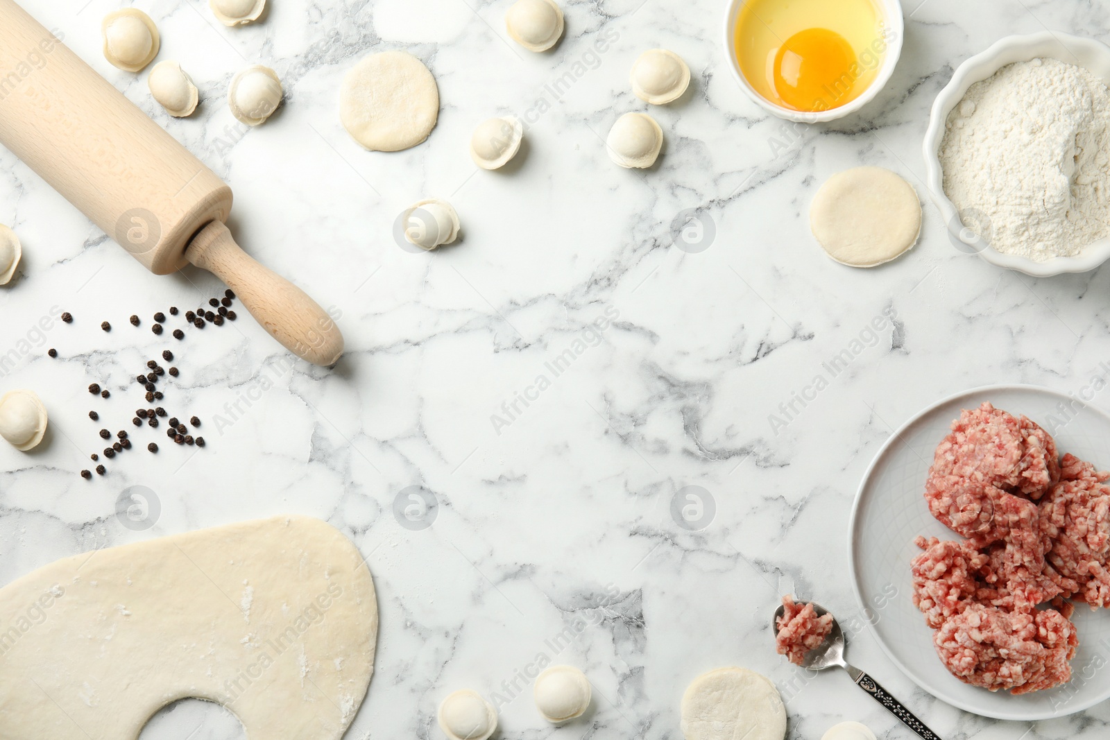 Photo of Flat lay composition with raw dumplings and ingredients on marble background, space for text. Process of cooking