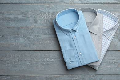 Photo of Stylish male shirts on grey wooden background, flat lay. Space for text