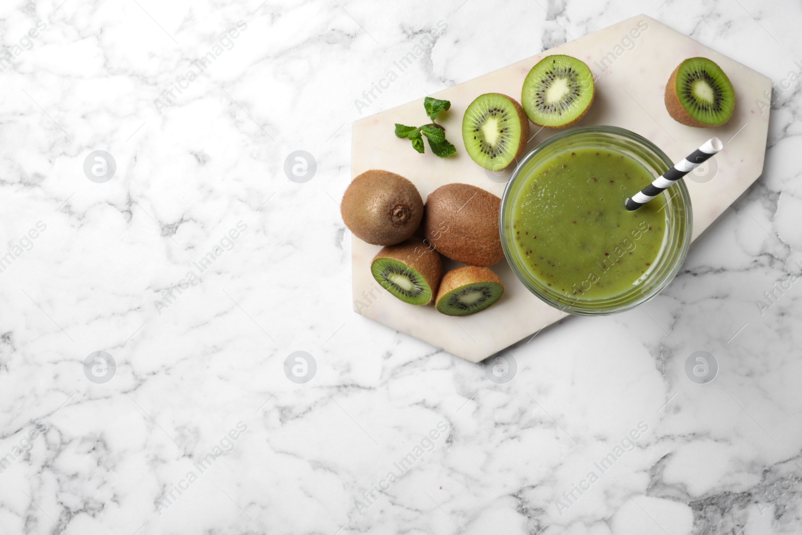 Photo of Delicious kiwi smoothie and fresh fruits on white marble table, top view. Space for text