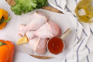 Photo of Flat lay composition with marinade and raw chicken drumsticks on white table