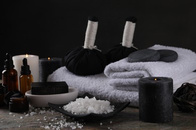 Composition with different spa products and burning candles on grey textured table