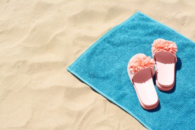 Photo of Towel and stylish slippers on sand, space for text. Beach accessories