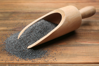 Poppy seeds in scoop on wooden table, closeup