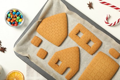 Photo of Parts of gingerbread house and ingredients on white table, flat lay