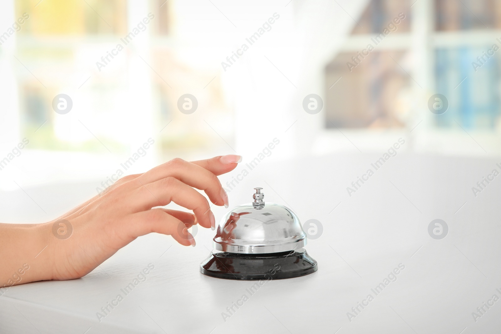 Photo of Young woman ringing service bell at reception desk, closeup