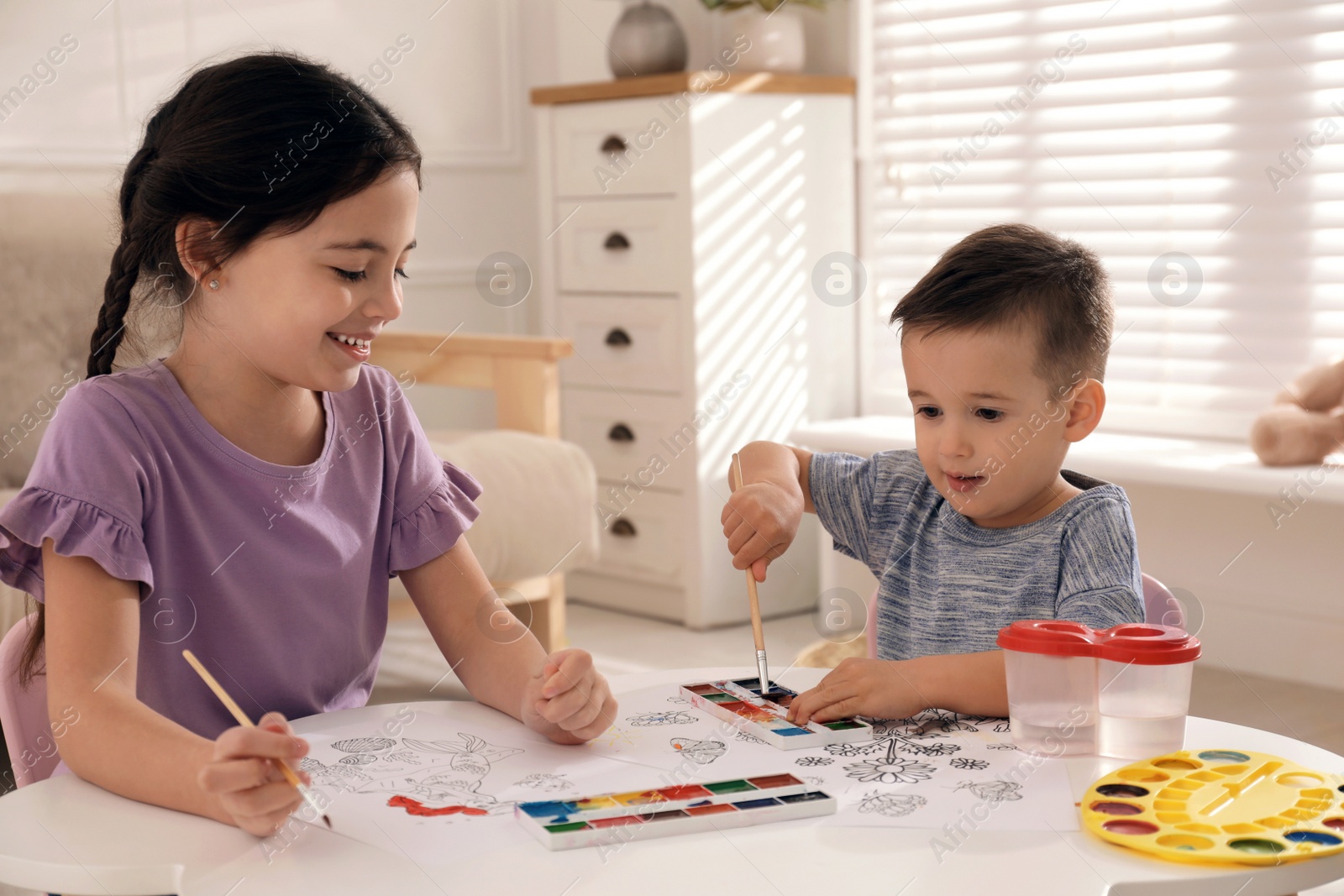 Photo of Cute children coloring drawing at table in room