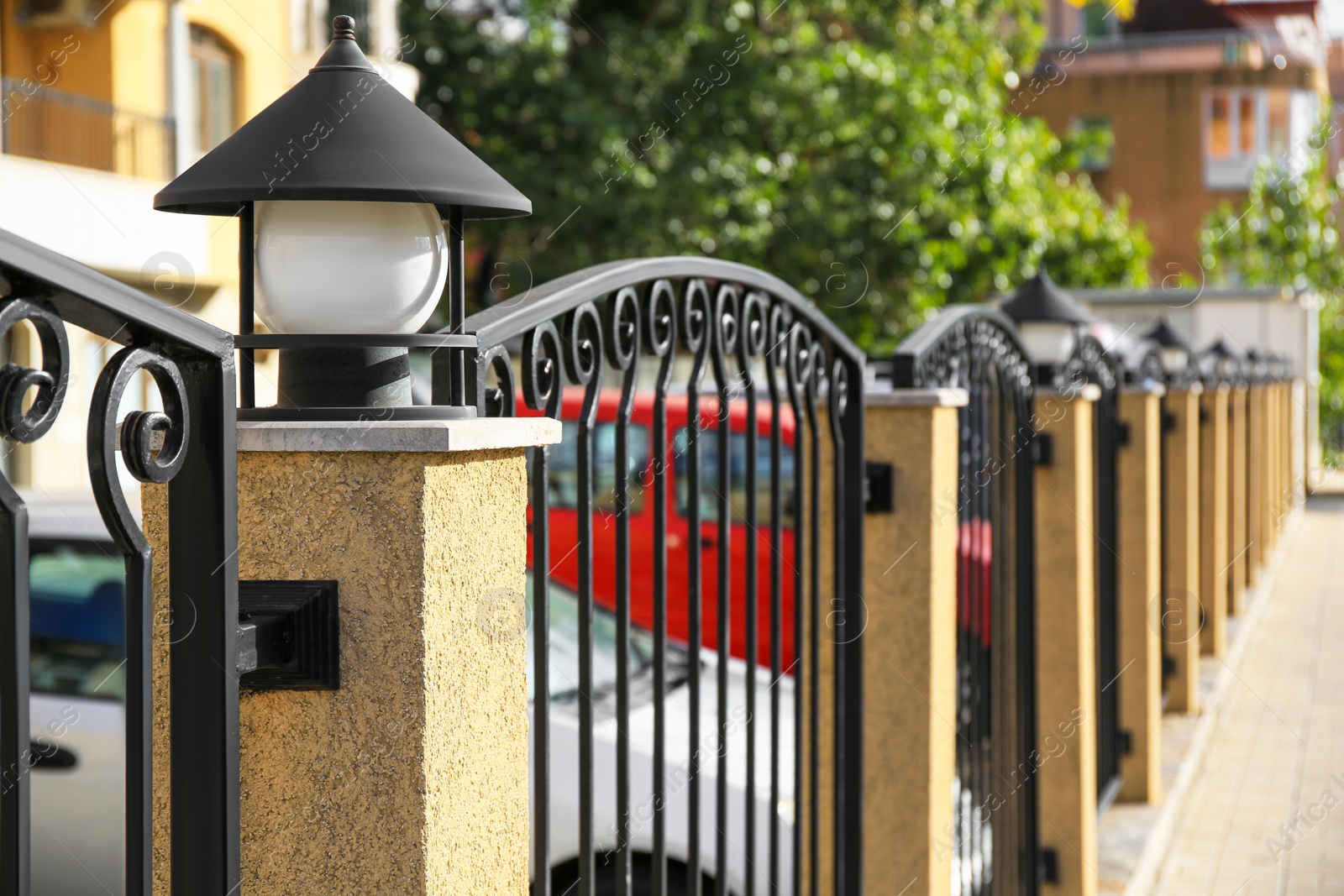 Photo of Pillar with streetlight on metal fence outdoors. space for text
