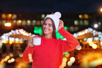 Happy beautiful woman with mug of mulled wine at Christmas fair