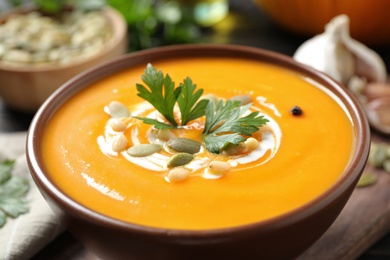 Delicious pumpkin soup in bowl on table, closeup