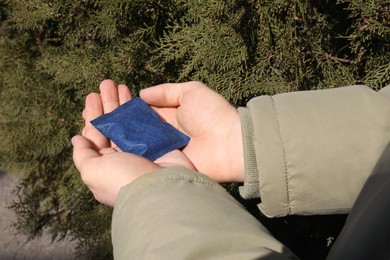 Photo of Man holding hand warmer outdoors, closeup view