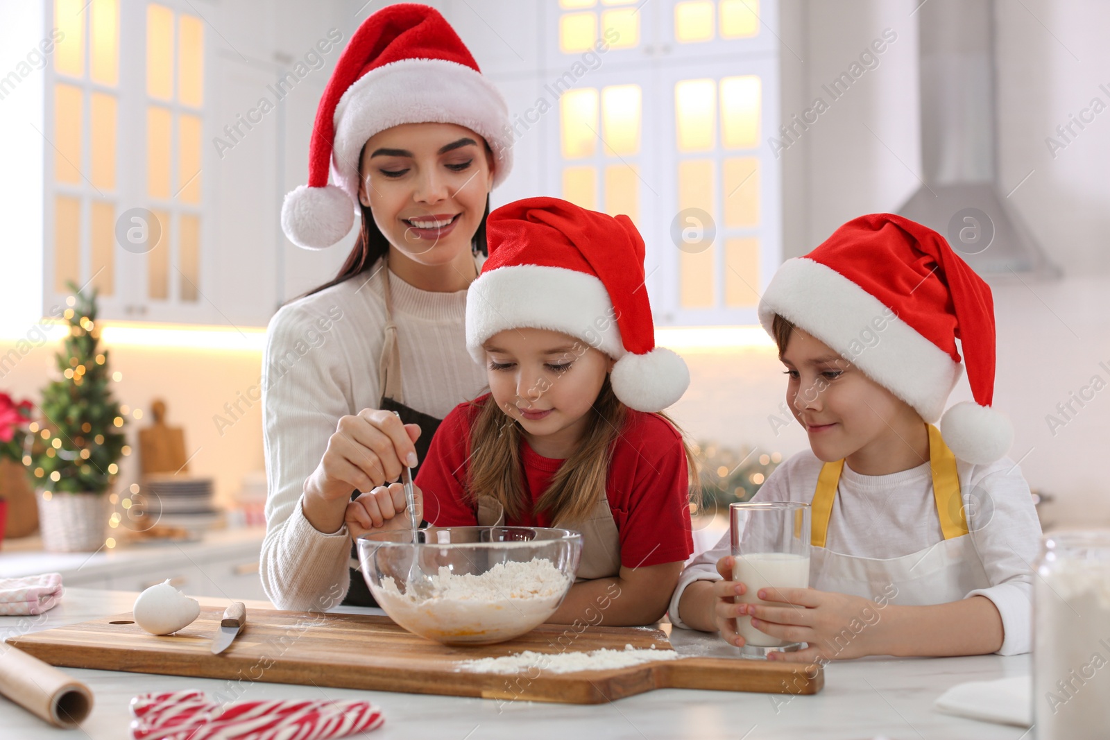 Photo of Mother with her cute little children making Christmas cookies in kitchen