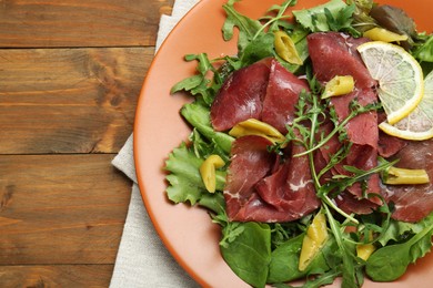 Photo of Delicious bresaola salad on wooden table, top view
