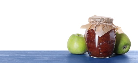 Photo of Jar with delicious apple jam and fresh fruits on blue wooden table against white background