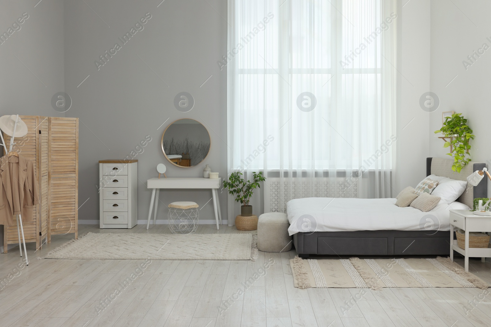 Photo of Stylish bedroom interior with large comfortable bed and ottoman near window