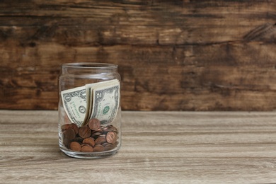 Donation jar with money on table. Space for text