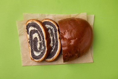 Photo of Cut poppy seed roll on light green background, top view. Tasty cake
