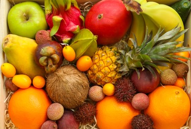 Photo of Assortment of exotic fruits in wooden crate, top view