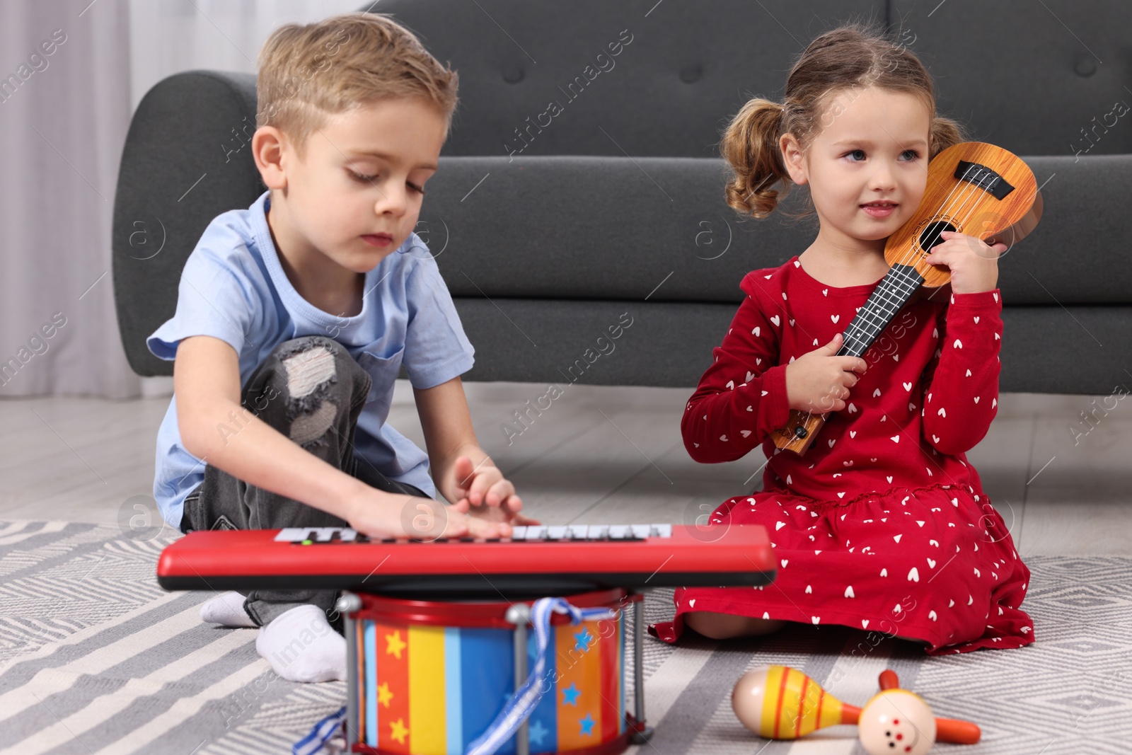 Photo of Little children playing toy musical instruments at home