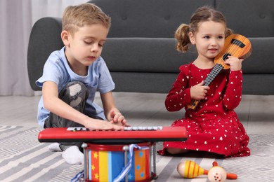 Little children playing toy musical instruments at home