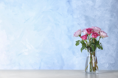 Photo of Beautiful roses in glass vase on light grey table. Space for text