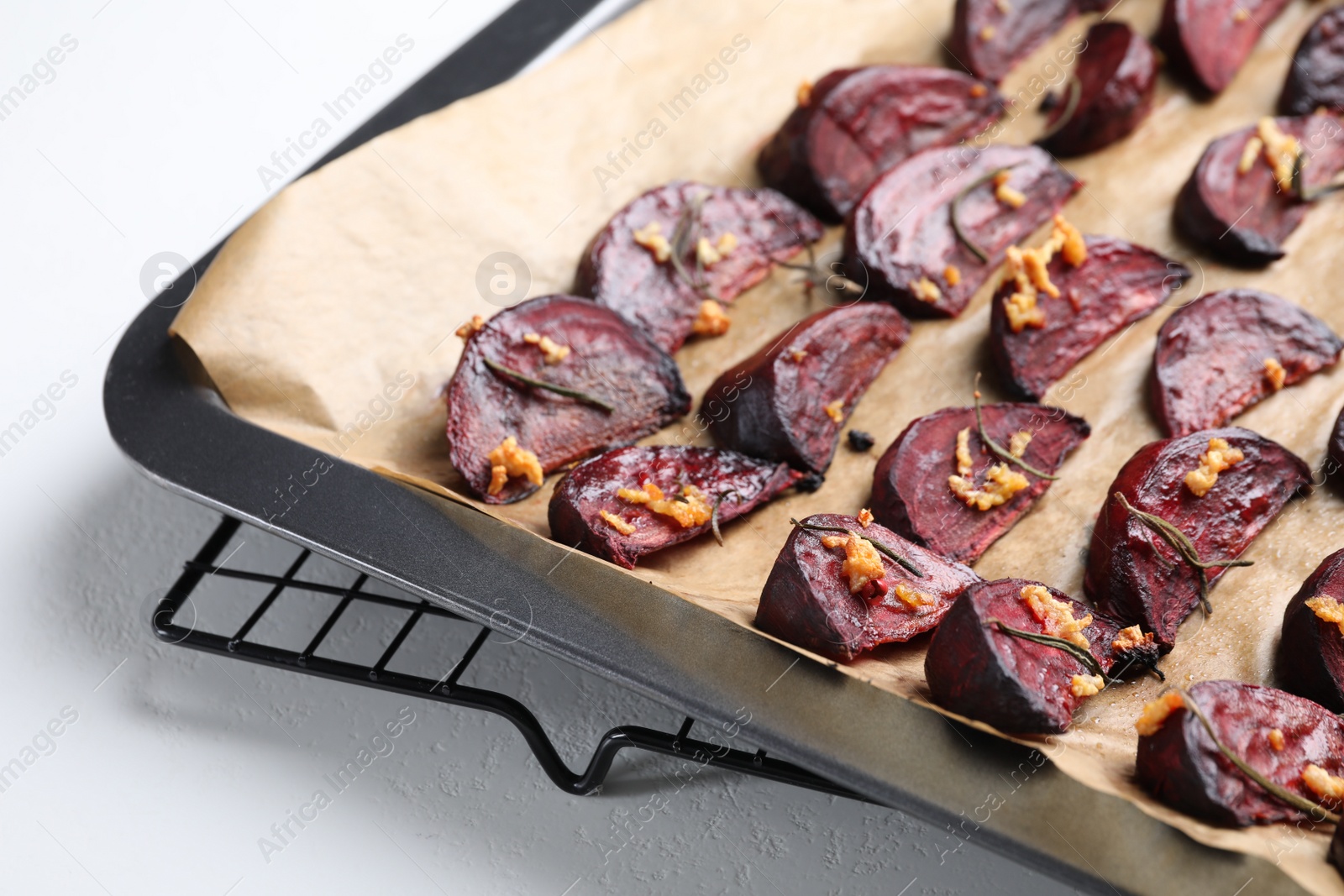 Photo of Baking tray with roasted beetroot slices on white table, closeup