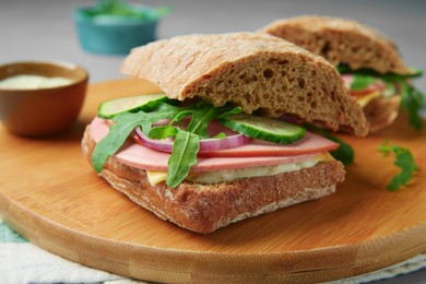 Tasty sandwiches with boiled sausage, cucumber and arugula on table, closeup