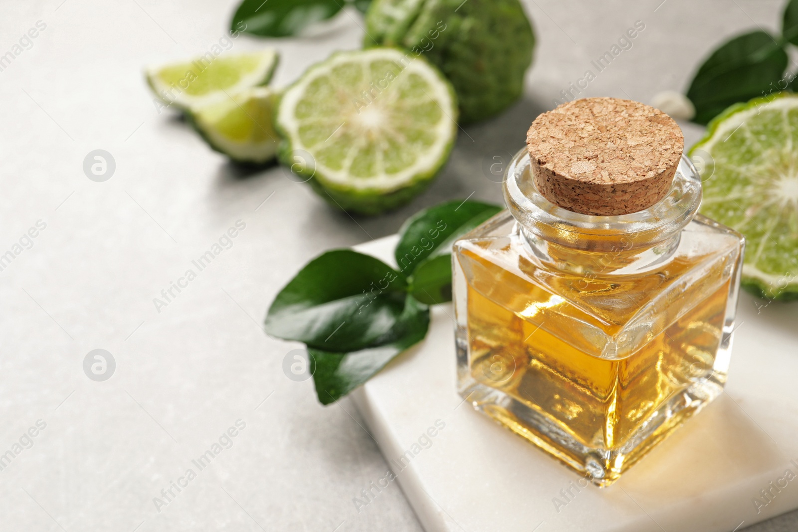 Photo of Bottle of bergamot essential oil on grey table. Space for text