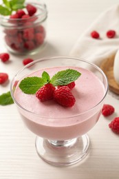 Photo of Delicious raspberry mousse with mint on white wooden table
