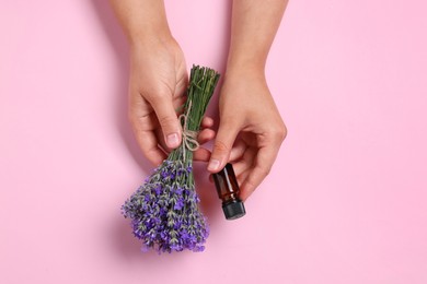 Photo of Woman with bottle of lavender essential oil and flowers on pink background, top view