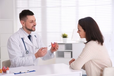 Doctor showing thyroid gland model to patient in hospital