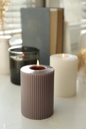 Different burning candles on window sill indoors