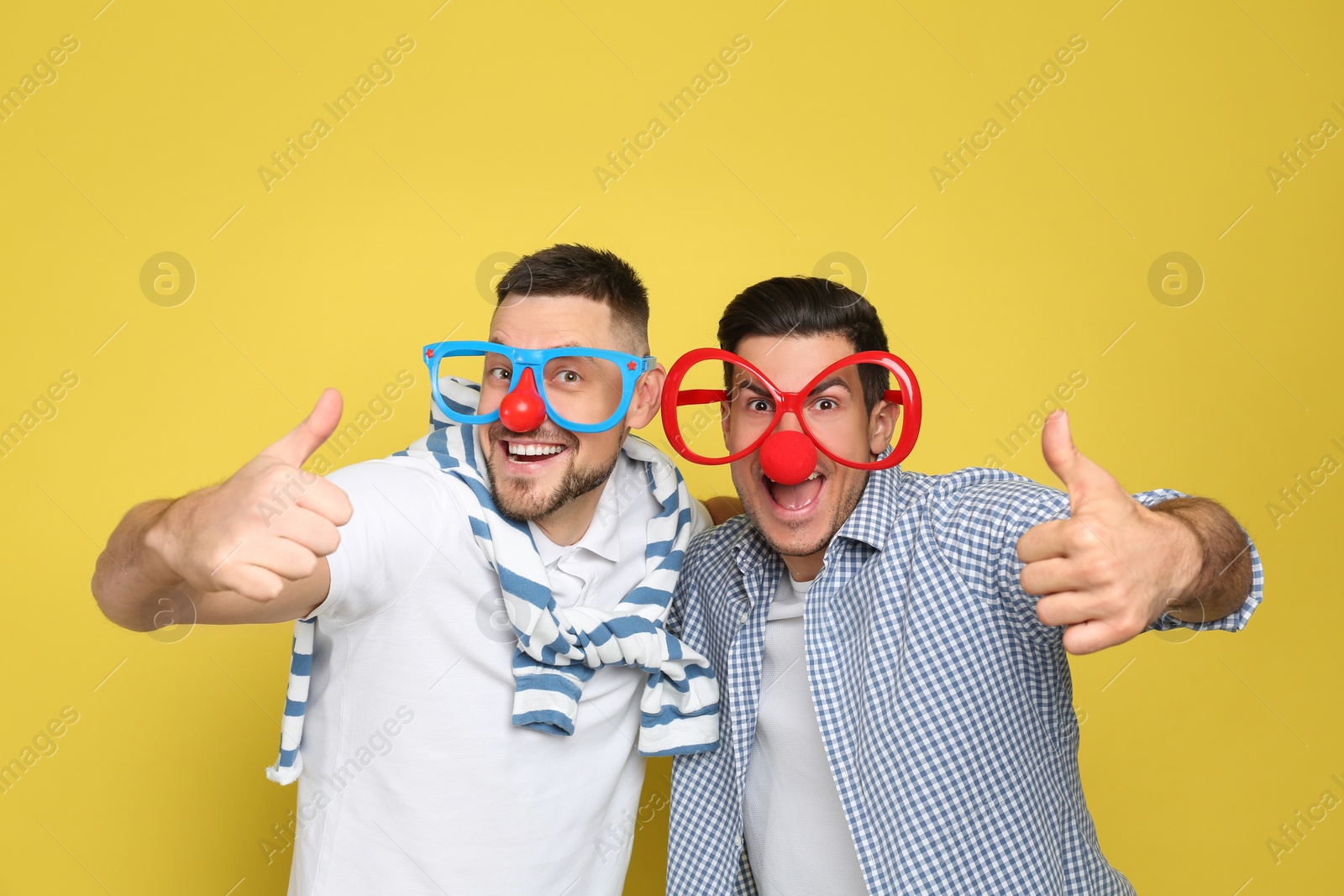 Photo of Men with funny accessories on yellow background. April fool's day