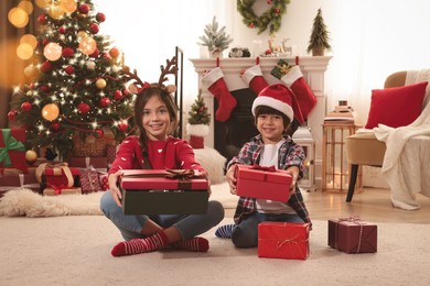 Photo of Happy children with Christmas gifts on floor at home