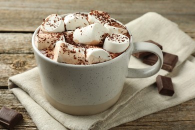 Photo of Delicious hot chocolate with marshmallows, cocoa powder and pieces on wooden table, closeup