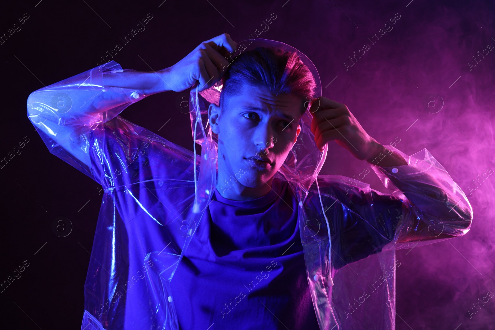 Photo of Young man wearing clear coat in neon lights with smoke effect