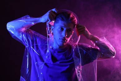 Young man wearing clear coat in neon lights with smoke effect