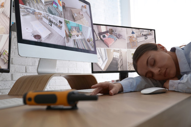 Photo of Female security guard sleeping near monitors at workplace