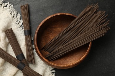 Photo of Uncooked buckwheat noodles (soba) on black table, flat lay
