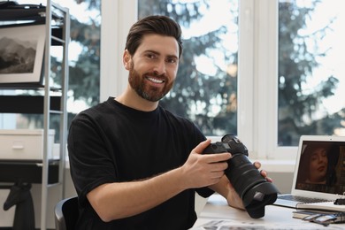 Photo of Professional photographer with digital camera at table indoors