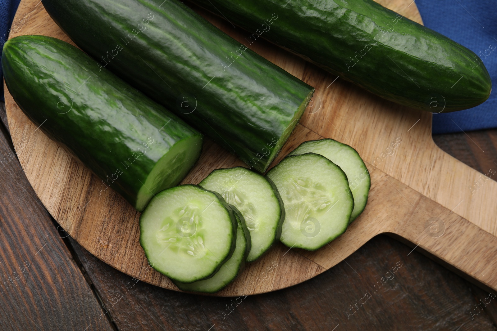 Photo of Fresh whole and cut cucumbers on wooden table, top view