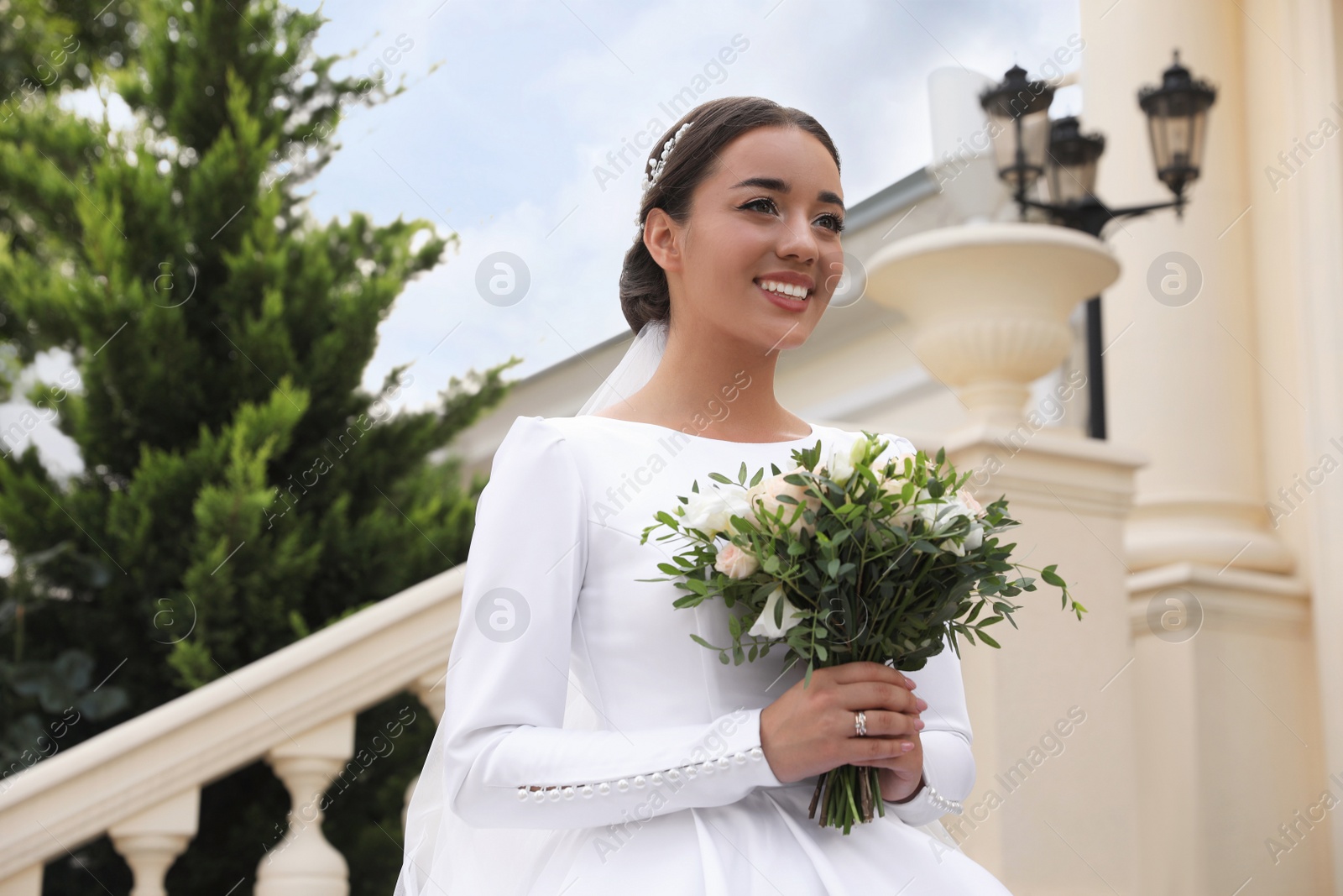Photo of Young bride wearing wedding dress and engagement ring with beautiful bouquet outdoors