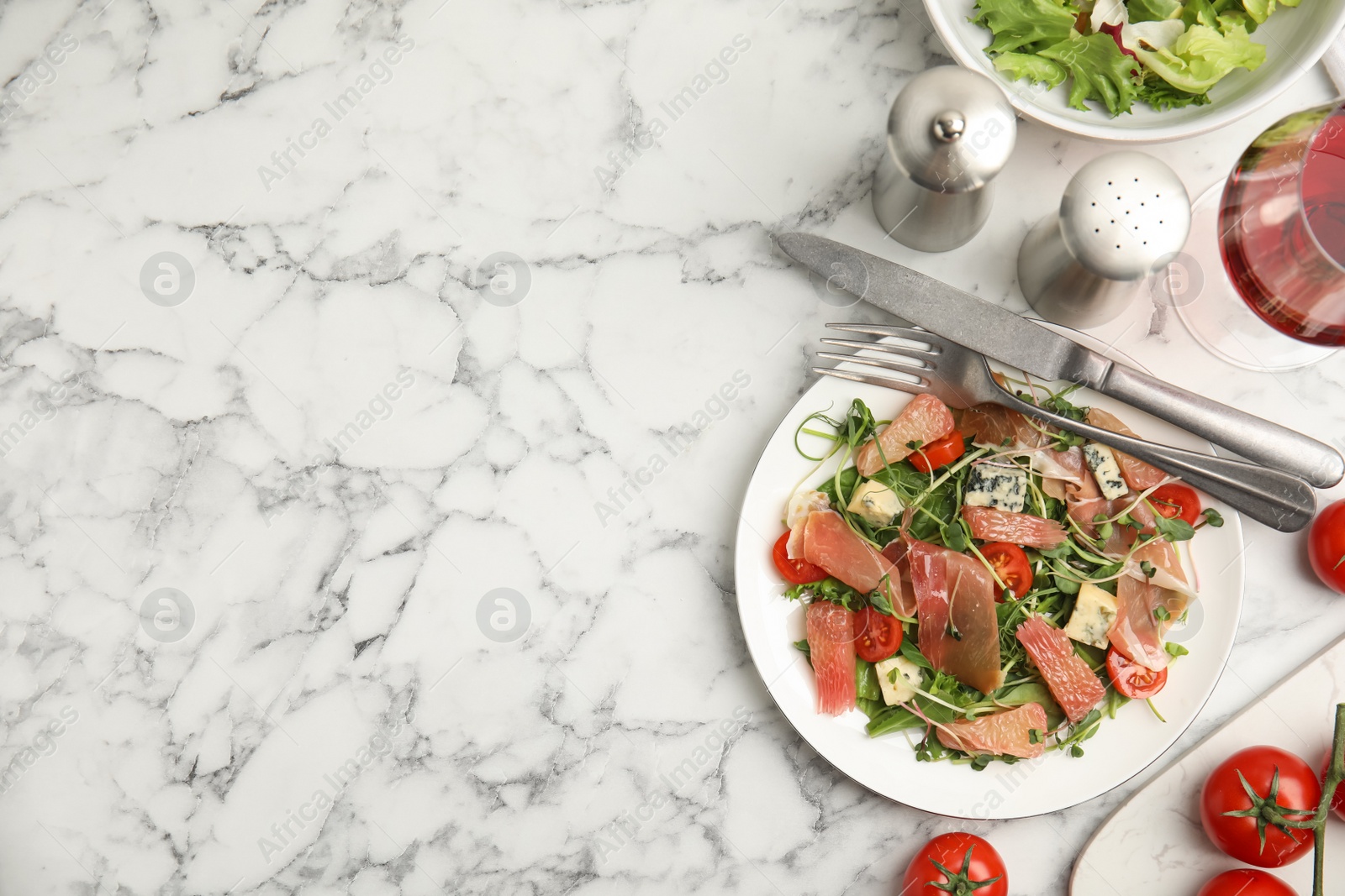 Photo of Delicious pomelo salad with prosciutto served on white marble table, flat lay. Space for text