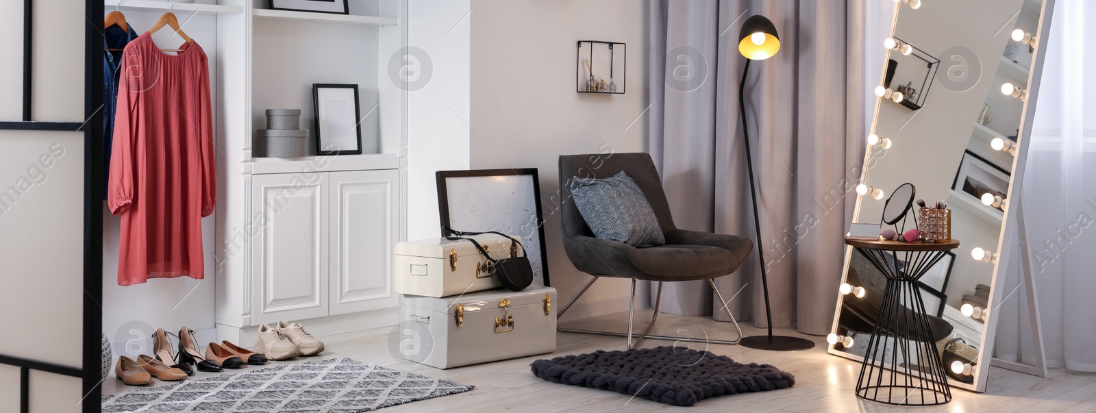 Image of Makeup room. Stylish mirror with light bulbs, beauty products on side table and armchair indoors, banner design