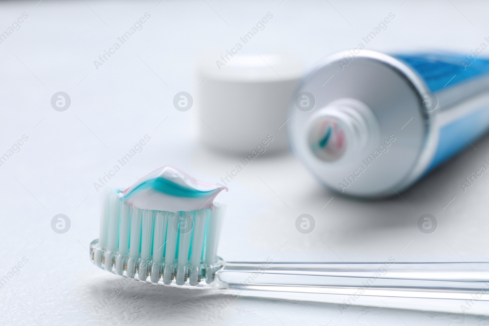 Photo of Brush with toothpaste and tube on white background, closeup