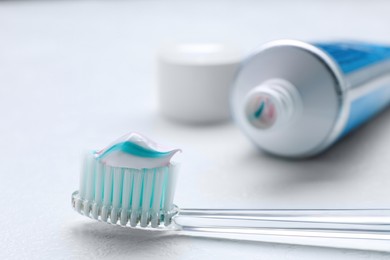 Photo of Brush with toothpaste and tube on white background, closeup