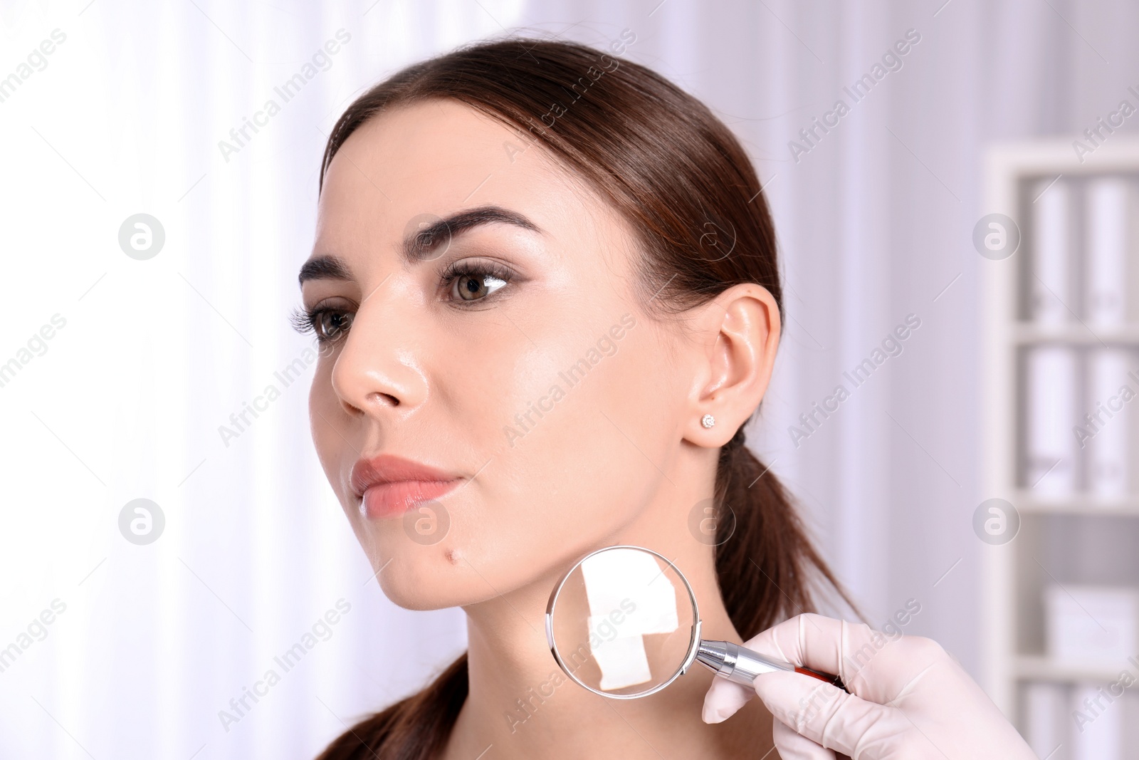 Photo of Dermatologist examining patient with magnifying glass in clinic