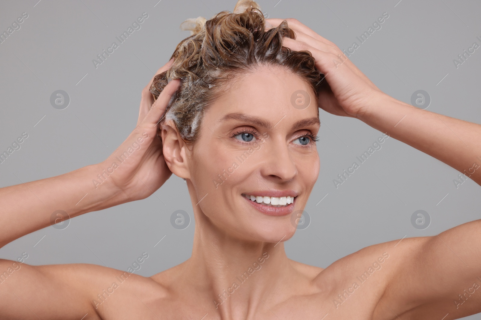 Photo of Beautiful happy woman washing hair on light grey background