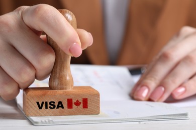 Image of Woman stamping document at white wooden table, closeup. Visa for Canada