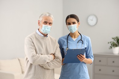 Photo of Nurse and elderly patient wearing protective masks in hospital
