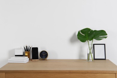 Comfortable workplace with wooden desk near white wall at home